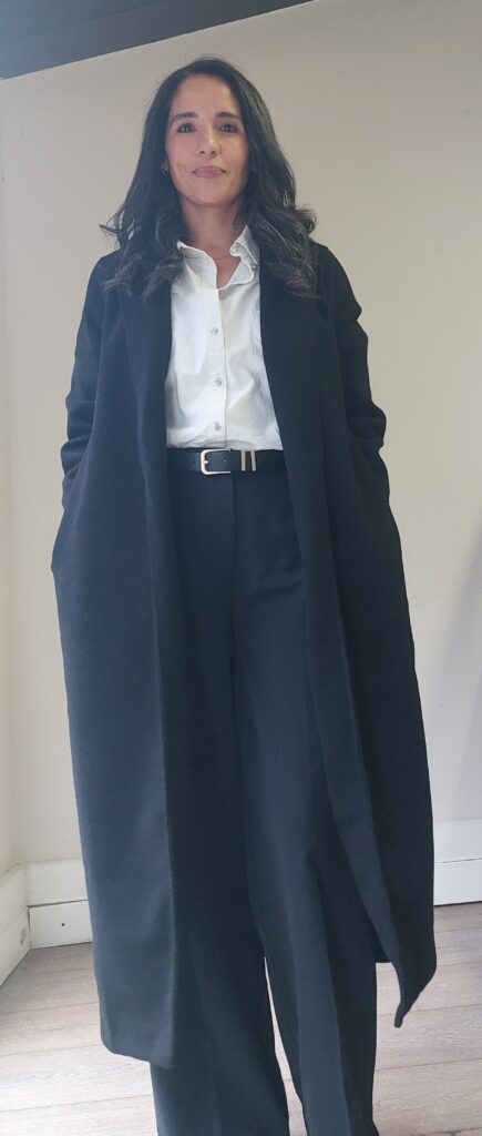 Nicole Abrahams in a black long coat and wide leg trousers — how to look put together over 40
